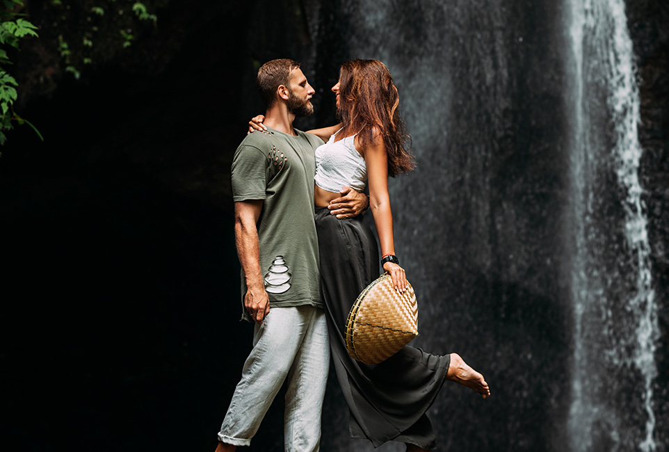 a-man-embraces-a-woman-at-a-waterfall-a-couple-in--NGWZE8J